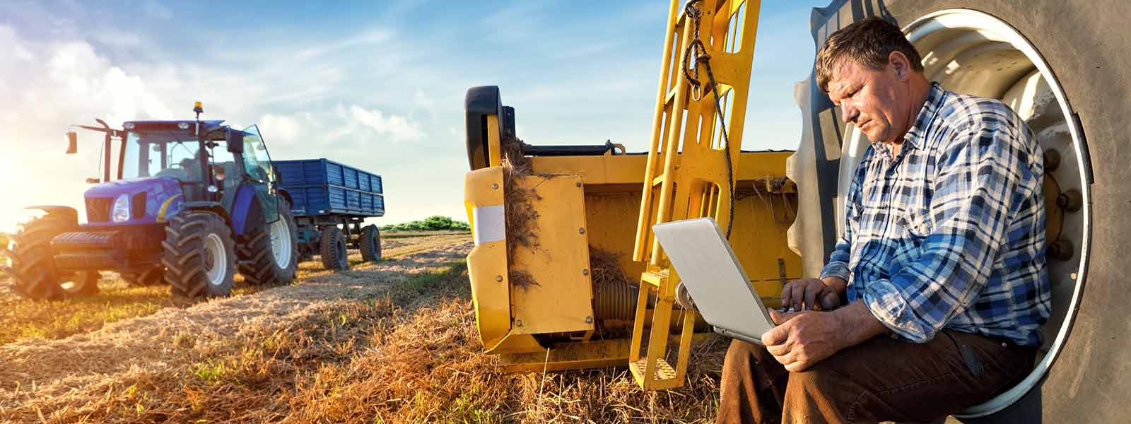 A farmer uses a computer in the field
