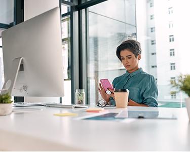 Woman looking at her phone while sitting at her desk