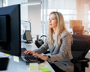 Women sitting in her office looking and typing on her computer