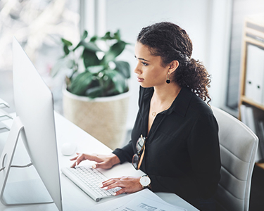 Woman sitting at her desk typing on a computer