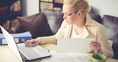 Woman at computer and holding a piece of paper