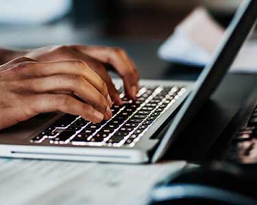 Hands typing on a laptop keyboard